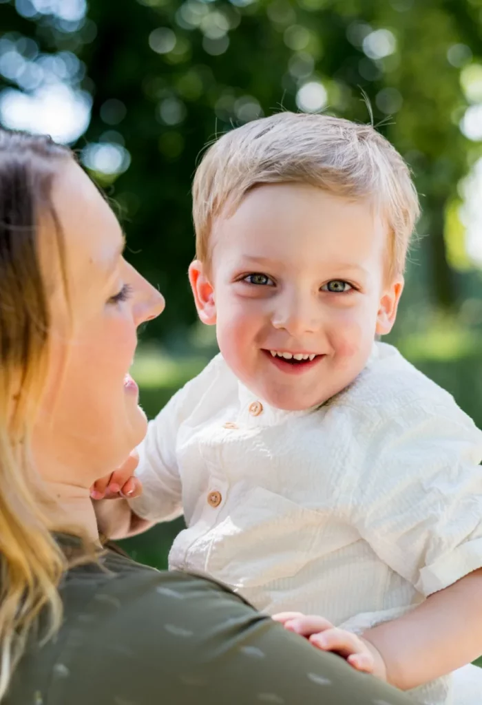 Kleines Kind lächelt auf dem Arm der Mutter bei einem natürlichen Familienshooting