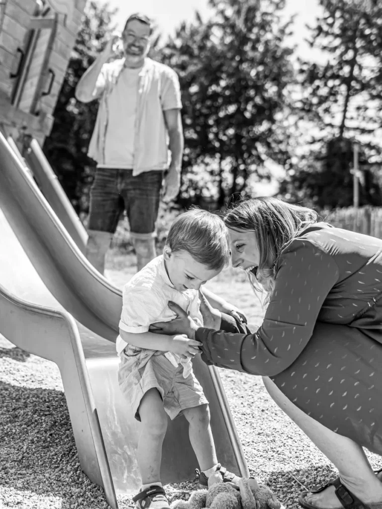 Mutter begleitet ihr Kind liebevoll auf einer Rutsche bei einem natürlichen Familienshooting