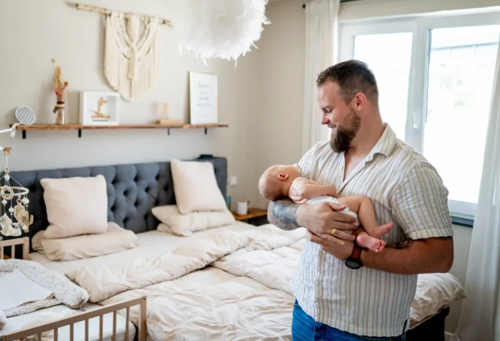 Vater hält sein Baby bei einem natürlichen Familienfotoshooting im Schlafzimmer