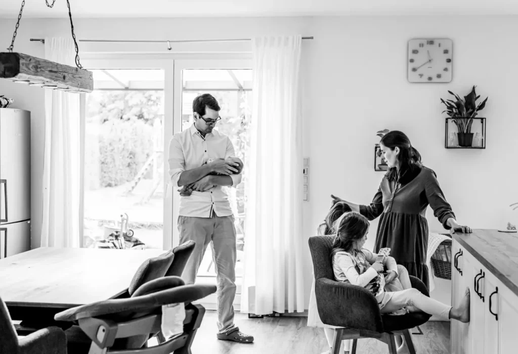 Familie verbringt gemeinsame Zeit zuhause mit Baby und Kindern in heller Wohnatmosphäre