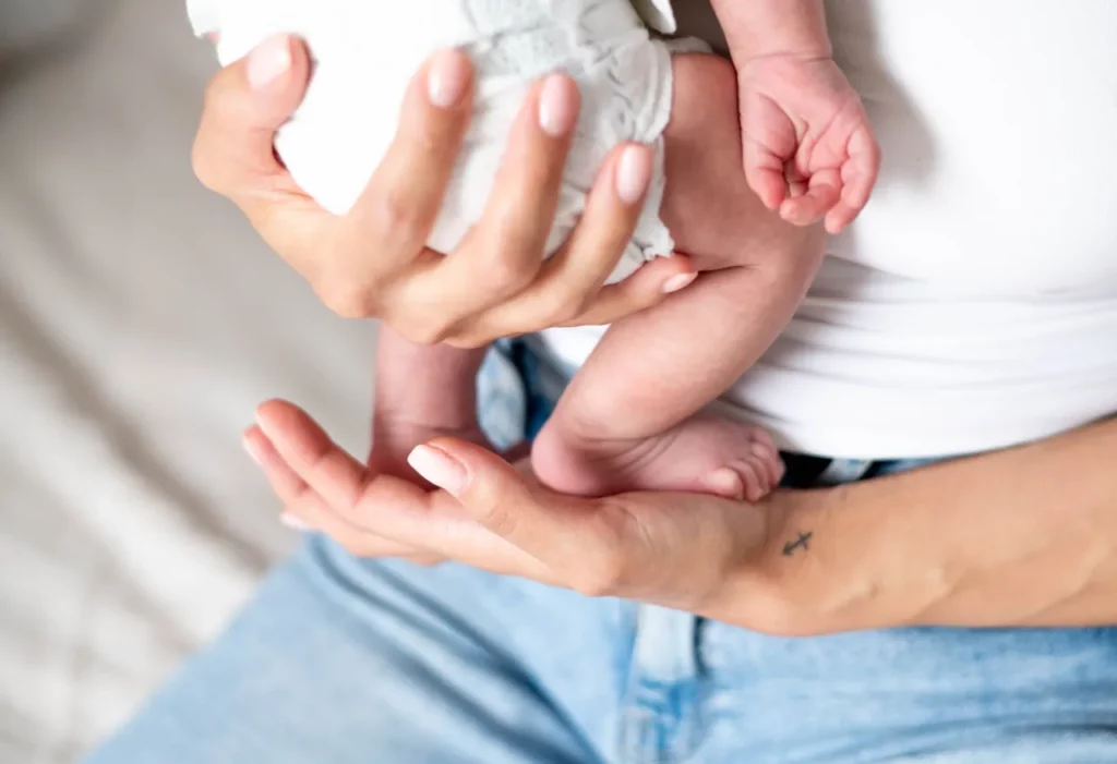 Kleine Hände und Füße eines Babys in den Händen der Mutter
