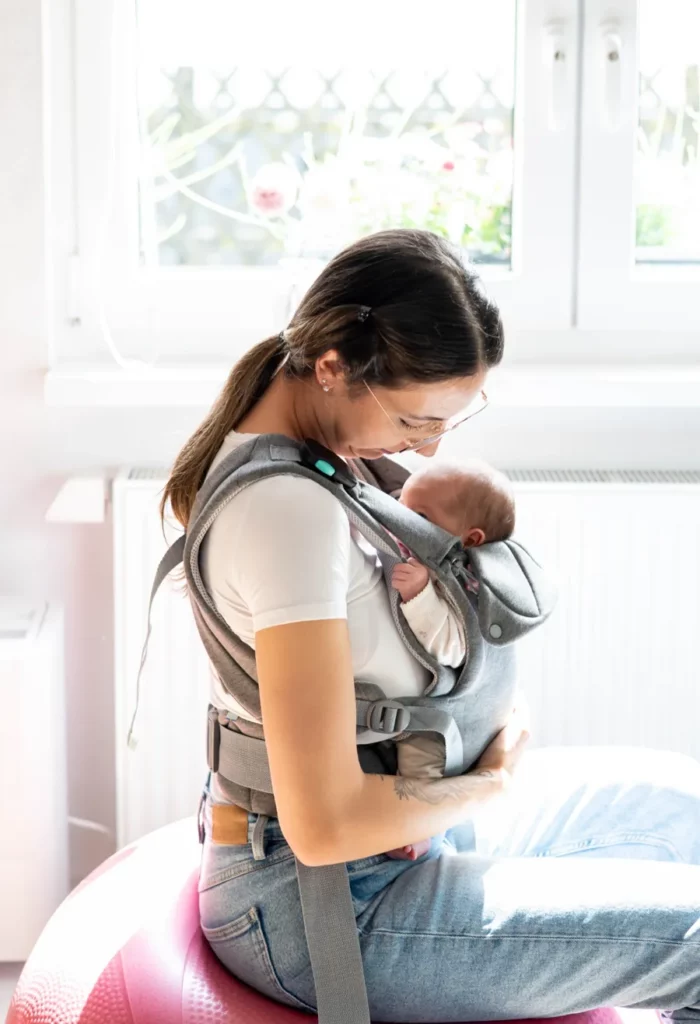 Detailaufnahme eines Babys in einer Trage mit Mutter
