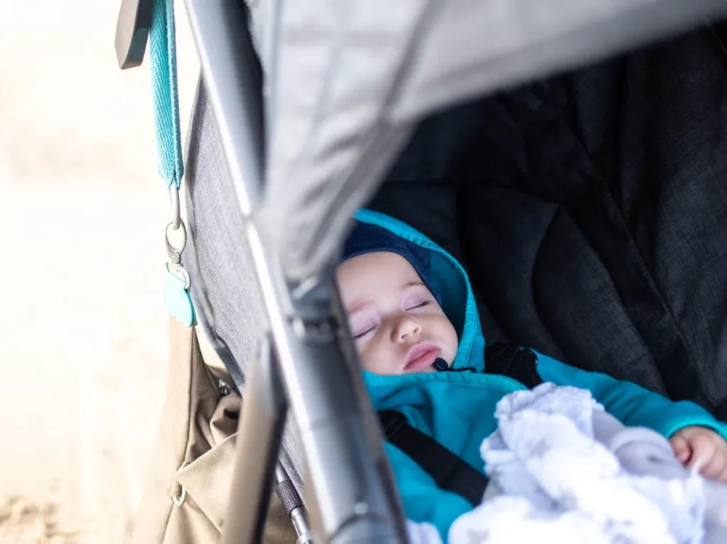 Schlafendes Baby entspannt im Kinderwagen bei einem Spaziergang
