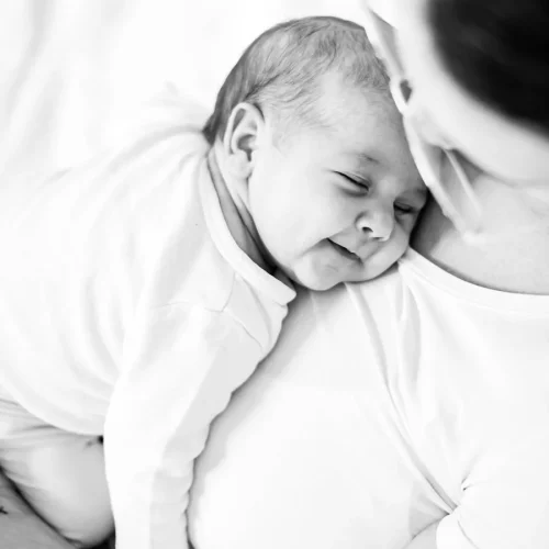 Lächelndes Baby auf der Schulter seiner Mutter