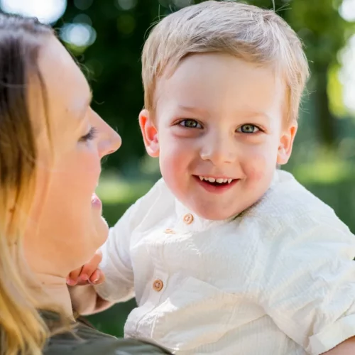 Kleines Kind lächelt auf dem Arm der Mutter bei einem natürlichen Familienshooting