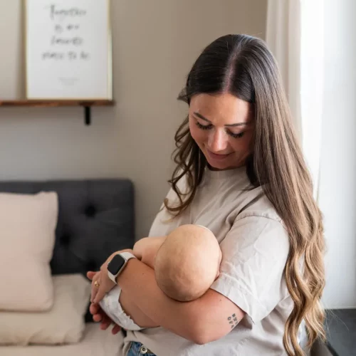 Mutter trägt ihr Baby liebevoll im Arm bei einem ruhigen Fotoshooting zuhause